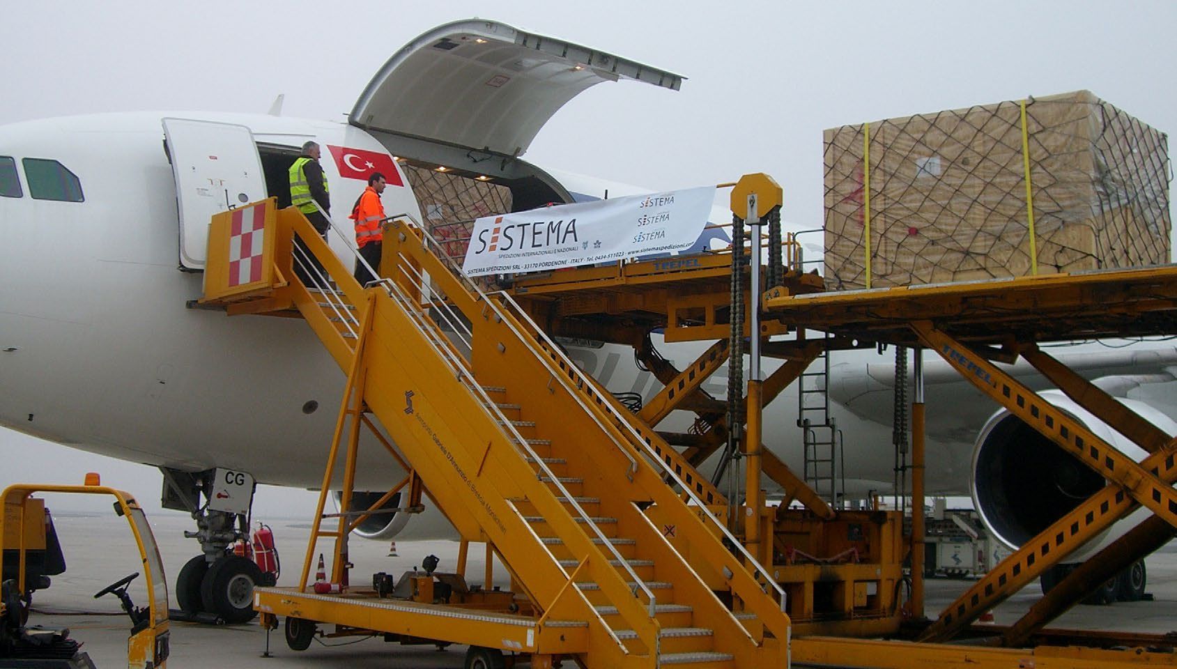 Cassa con il marchio Sistema caricata nella stiva di un aereo cargo