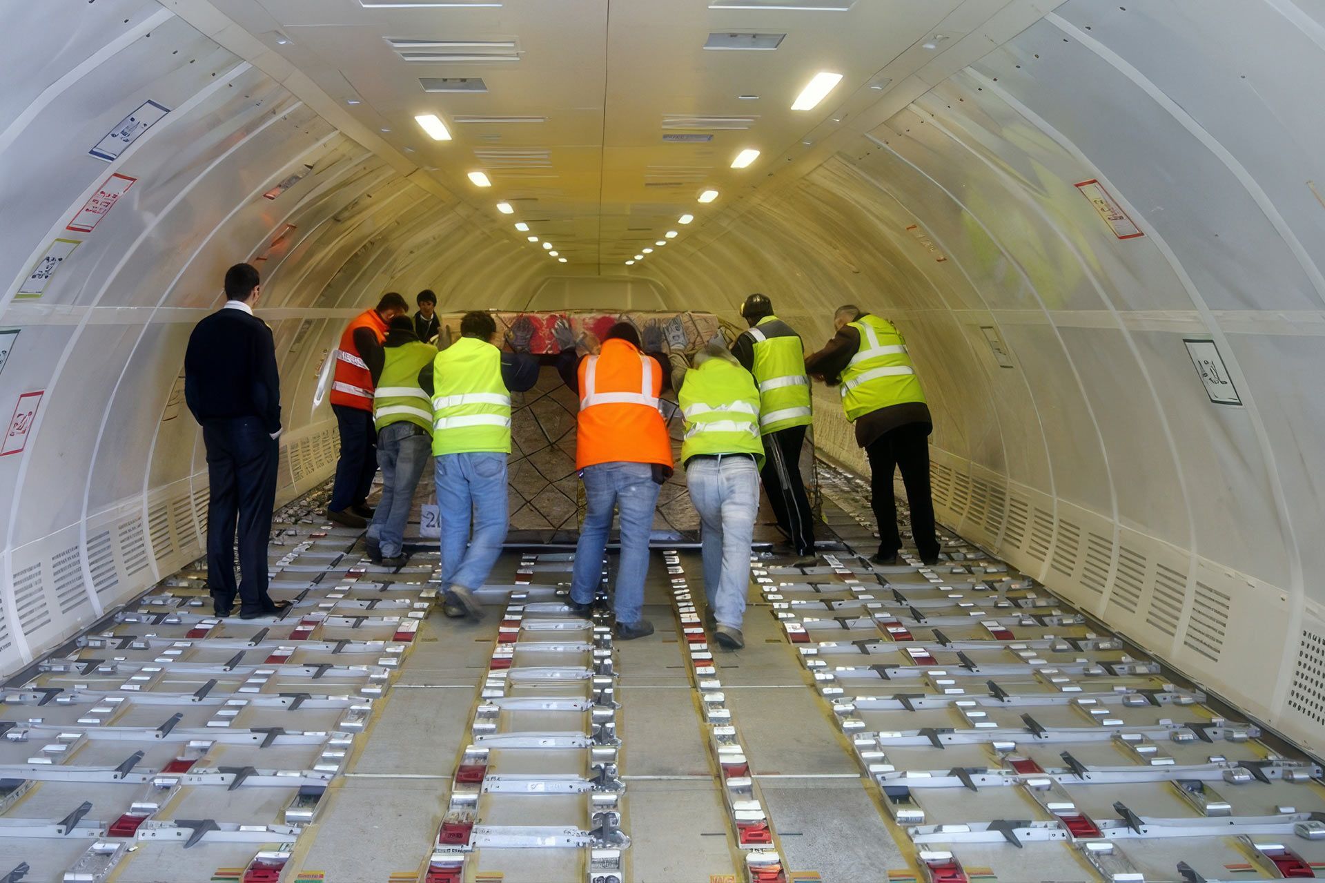Operatori in gilet ad alta visibilità sistemano i colli nella stiva di un aereo cargo