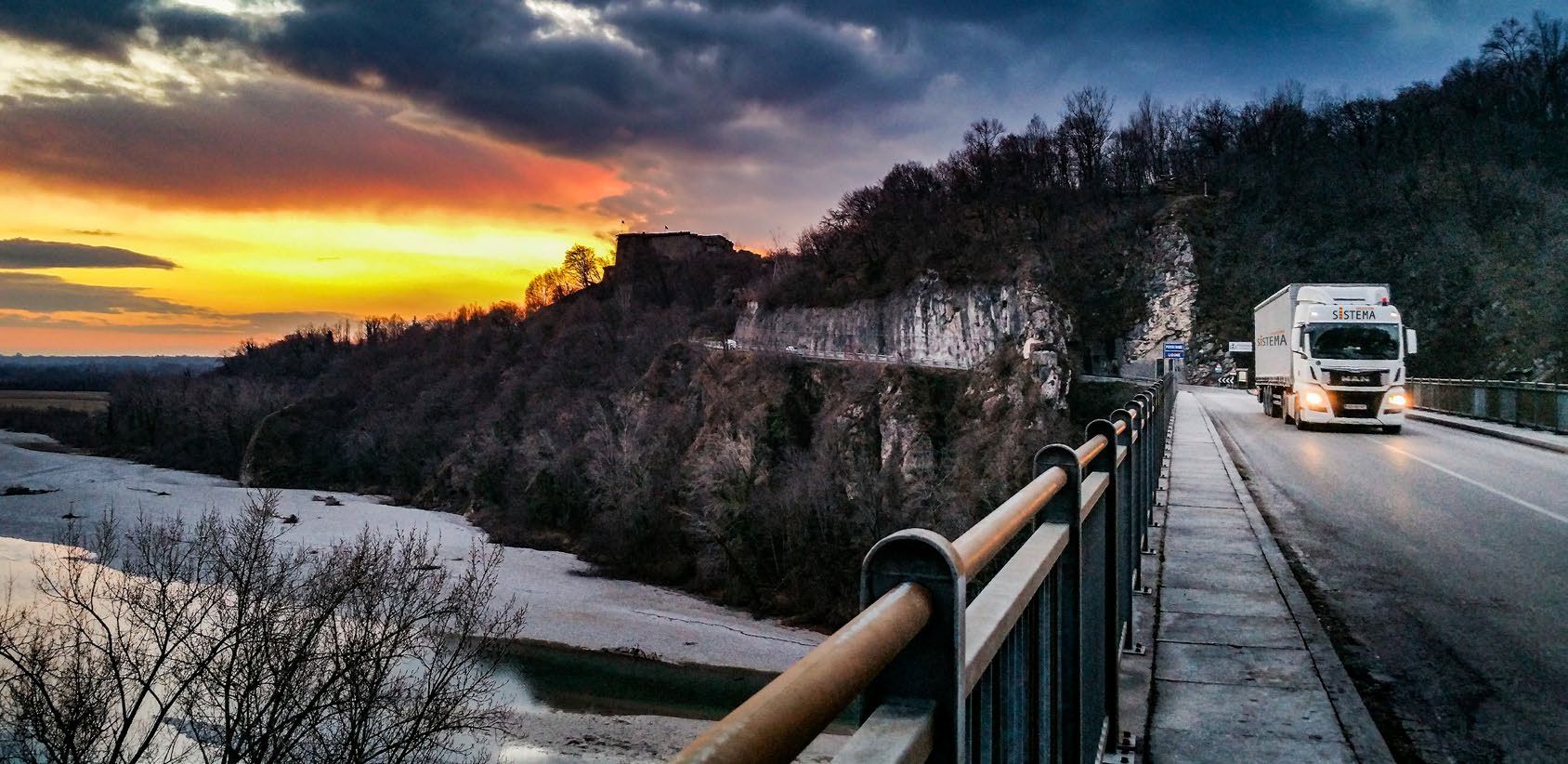 Camion su un ponte al tramonto, tra le colline