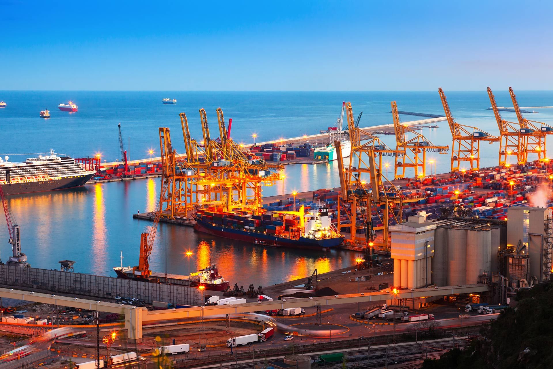 Porto container al tramonto con gru di banchina e navi ormeggiate
